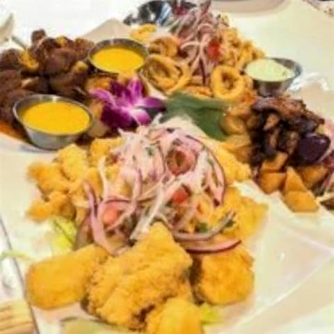 Fuente grande para compartir con pescado apanado, calamares, causa con salsa criolla y salsas en ramequines